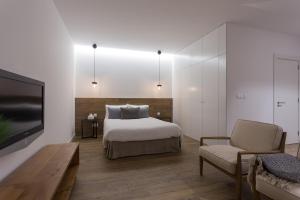 a bedroom with a bed and a tv and a chair at Quinta de Santa Clara in Ponta Delgada