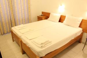 Una cama con sábanas blancas y toallas blancas. en Dimitra Hotel, en Faliraki