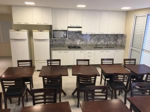a dining room with tables and chairs and a kitchen at Tapera Hostel in São Paulo