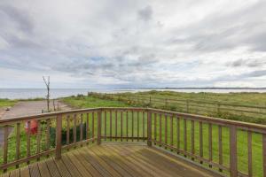 a wooden deck with a view of the ocean at Cloughey holiday lodge in Kirkistown