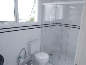 a white bathroom with a toilet and a window at CASA - FRENTE PARA O MAR in Itanhaém