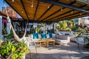 eine Terrasse mit einem Sofa, Stühlen und einer Hängematte in der Unterkunft Hotel Vista Oceana Sayulita in Sayulita