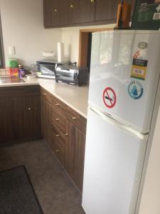 a kitchen with a white refrigerator with stickers on it at Dons Place in Waikawa