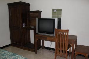 Un televisor sobre un escritorio de madera con una silla de madera. en Sinar Bintang Hotel, en Padangan