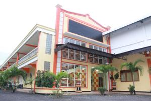 a building with palm trees in front of it at Sinar Bintang Hotel in Padangan