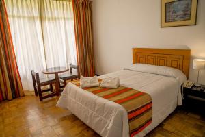 Real Hotel Huascaran في هواراس: غرفة نوم بها سرير وطاولة وكراسي +19 صورة