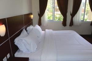 - une chambre avec un lit doté de draps et d'oreillers blancs dans l'établissement Diyar Villas Puncak M4/12, à Puncak
