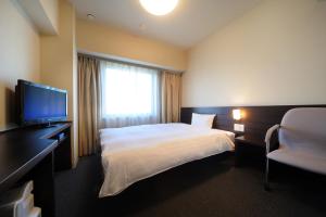 a hotel room with a bed and a flat screen tv at Dormy Inn Sendai Annex in Sendai