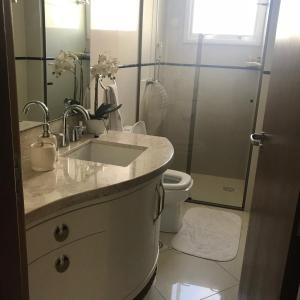 a bathroom with a sink and a toilet and a mirror at Lindo apartamento no centro de Canela in Canela +36 photos