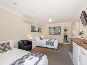 1 dormitorio con 2 camas y escritorio con TV en Narimba Motel, en Port Macquarie