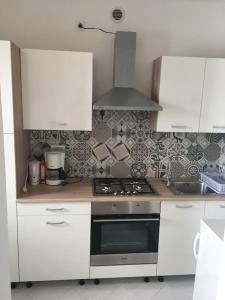 a kitchen with white cabinets and a stove top oven at Nela Apartment in Rabac