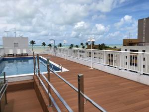 una gran terraza con piscina y el océano en Apto Lazer, en João Pessoa