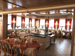 uma sala de jantar com mesas, cadeiras e janelas em Hotel Sonnental em Neusorg