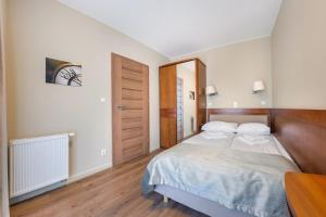 a bedroom with a large bed with a wooden headboard at Apartament Sun & Snow Gwiazda Morza in Władysławowo