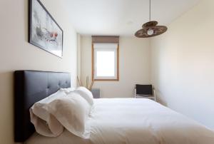 マルピカにある2- Apartamento Playa Canidoのベッドルーム1室(白いシーツとファン付きのベッド1台付)