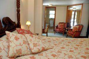 a bedroom with a bed with a bedspread and chairs at Hopbine House in Hereford