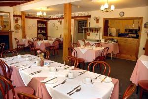 a restaurant with tables and chairs with pink tablecloths at Hopbine House in Hereford