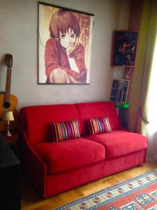 un sofá rojo en una sala de estar con una pintura en St Pothin Village avec garage, en Lyon