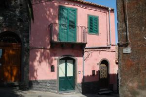 ein rosafarbenes Gebäude mit grünen Rollläden und einer Tür in der Unterkunft Casa Maria in Puntalazzo