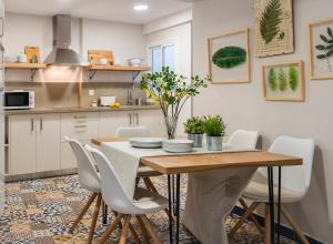 a kitchen with a wooden table and white chairs at Genteel Home Picasso in Málaga