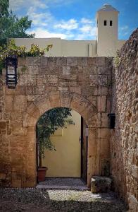 a stone wall with an arch with a potted plant at Lemuria Manor, Wine Dark Sea Villas in Rhodes Town