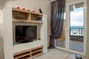 a living room with a tv and a balcony at Varka Apartment in Makrýgialos