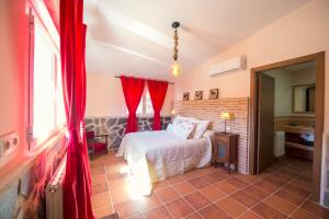 a bedroom with a bed with red drapes at Casa Rural Encinar de las Flores in Los Navalucillos