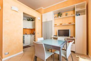 a dining room with a table and chairs and a kitchen at Bomboniera fronte mare ! in Viareggio