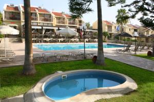 a swimming pool with chairs and umbrellas next to a hotel at Club Aphrodite in Erimi