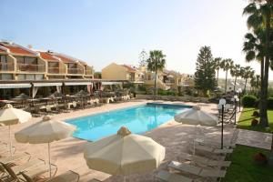 a swimming pool with umbrellas and chairs and a hotel at Club Aphrodite in Erimi
