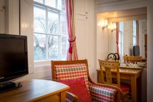 a living room with a table and a television and a table and chairs at The Abbey Hotel in Tewkesbury