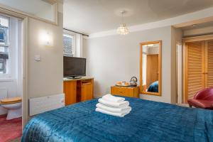 a bedroom with a blue bed and a television at The Abbey Hotel in Tewkesbury