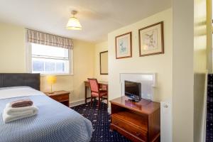 a hotel room with a bed and a desk with a television at The Abbey Hotel in Tewkesbury
