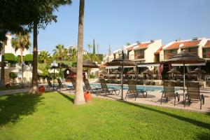 a group of chairs and umbrellas next to a pool at Club Aphrodite in Erimi