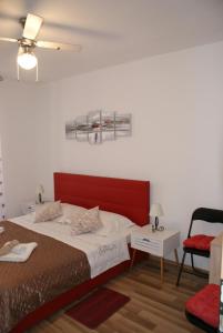 a bedroom with a red bed and a chair at Apartman Old Town in Trogir