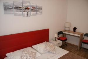 a bedroom with a bed with a red headboard and a table at Apartman Old Town in Trogir