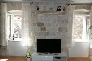 a living room with a tv on a stone wall at Apartman Old Town in Trogir
