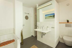 a white bathroom with a toilet and a sink at Lotsenstieg 04 in Ostseebad Karlshagen