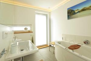 a white bathroom with a tub and a sink at Lotsenstieg 04 in Ostseebad Karlshagen