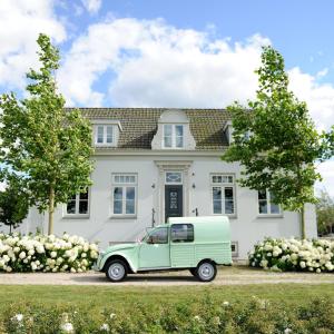 een oude groene truck geparkeerd voor een wit huis bij Boutique hotel Villa Oldenhoff in Abcoude