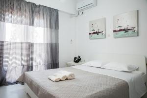 a white bedroom with a bed with towels on it at Cosy apartment in Glyfada center in Athens