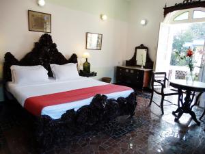 a bedroom with a bed and a table and a window at WelcomHeritage Panjim Inn in Panaji