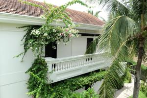 een wit huis met een balkon met bloemen bij Boutique Hoi An Resort in Hội An