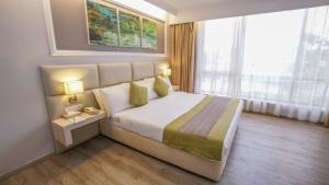 a bedroom with a large bed and a large window at Kingwood Hotel Kuching in Kuching