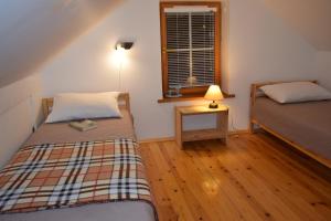 a bedroom with two beds and a table with a lamp at Svečių namelis in Druskininkai