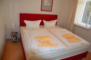 ヘリングスドルフにあるVilla Sabinium Appartement 1 und 4のベッド(白いシーツ、オレンジ色のバスローブ付)