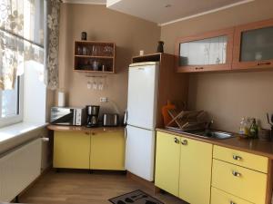 La cuisine est équipée de placards jaunes et d'un réfrigérateur blanc. dans l'établissement Akord Apartments, à Pärnu