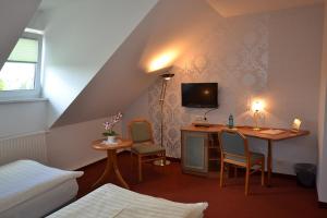 a bedroom with a desk with chairs and a tv at Hotel & Restaurant Zur Linde in Freital
