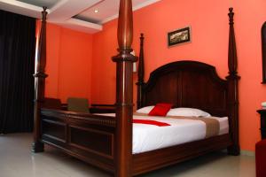 um quarto com uma cama com uma parede laranja em RedDoorz @ Sersan Bajuri em Bandung