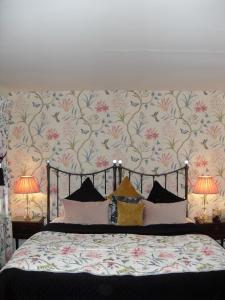 a bedroom with a bed with floral wallpaper and two lamps at Jessop House in Tewkesbury